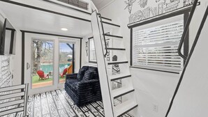 A modern interior with a black and white patterned floor, a black sofa, and a staircase with black railings. - The Doodle House | Lake Front Tiny Home (Bastrop County)