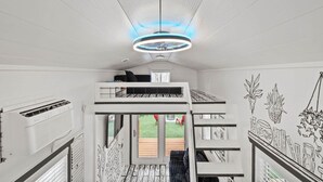 A room with bunk beds, a ceiling fan, and a view of the outdoors. - The Doodle House | Lake Front Tiny Home (Bastrop County)