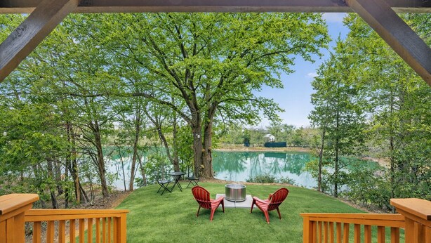 A deck with a view of a lake, surrounded by trees. - The Doodle House | Lake Front Tiny Home (Bastrop County)