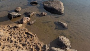 Une plage avec une eau claire, des rochers et une falaise rocheuse.