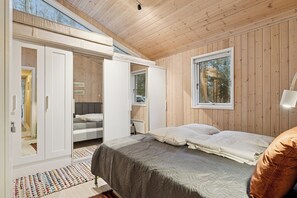 A bedroom with a bed, a wardrobe, a desk, and a window. - Cosy private cottage 800 m from the beach (Løkken)