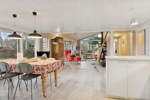 A spacious dining area with a wooden table, chairs, and pendant lighting. - Cosy private cottage 800 m from the beach (Løkken)