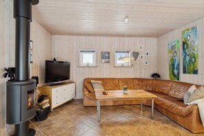 A living room with a sofa, a television, a fireplace, and artwork on the walls. - Cosy holiday home near Legoland (Hovborg)