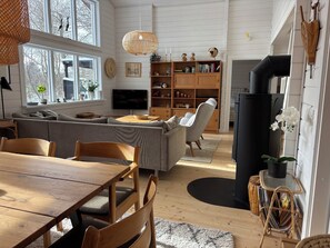 Ein Wohnzimmer mit einer Couch, einem Esstisch, Stühlen, einem Fernseher, einem Bücherregal und einem Kamin.