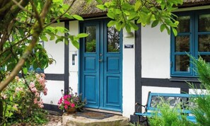 A traditional building with a blue door, white walls, and a thatched roof. - Cozy farmhouse close to the sea (Nakskov)