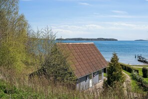 A house with a red roof, a visible deck, and a view of a lake. - Holiday home with lovely view of Lillebælt (Fredericia)