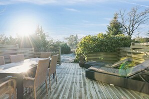 Een houten terras met rieten meubels, een tafel en stoelen.