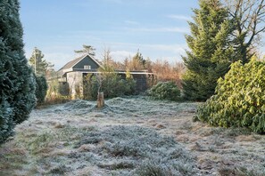 A house with a stone foundation, surrounded by dense evergreen trees and a frosty field. - Quiet holiday in Hemmet 300 m to water (Hemmet)