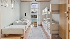 Un dormitorio con una cama litera, una cama individual, una ventana y una puerta.