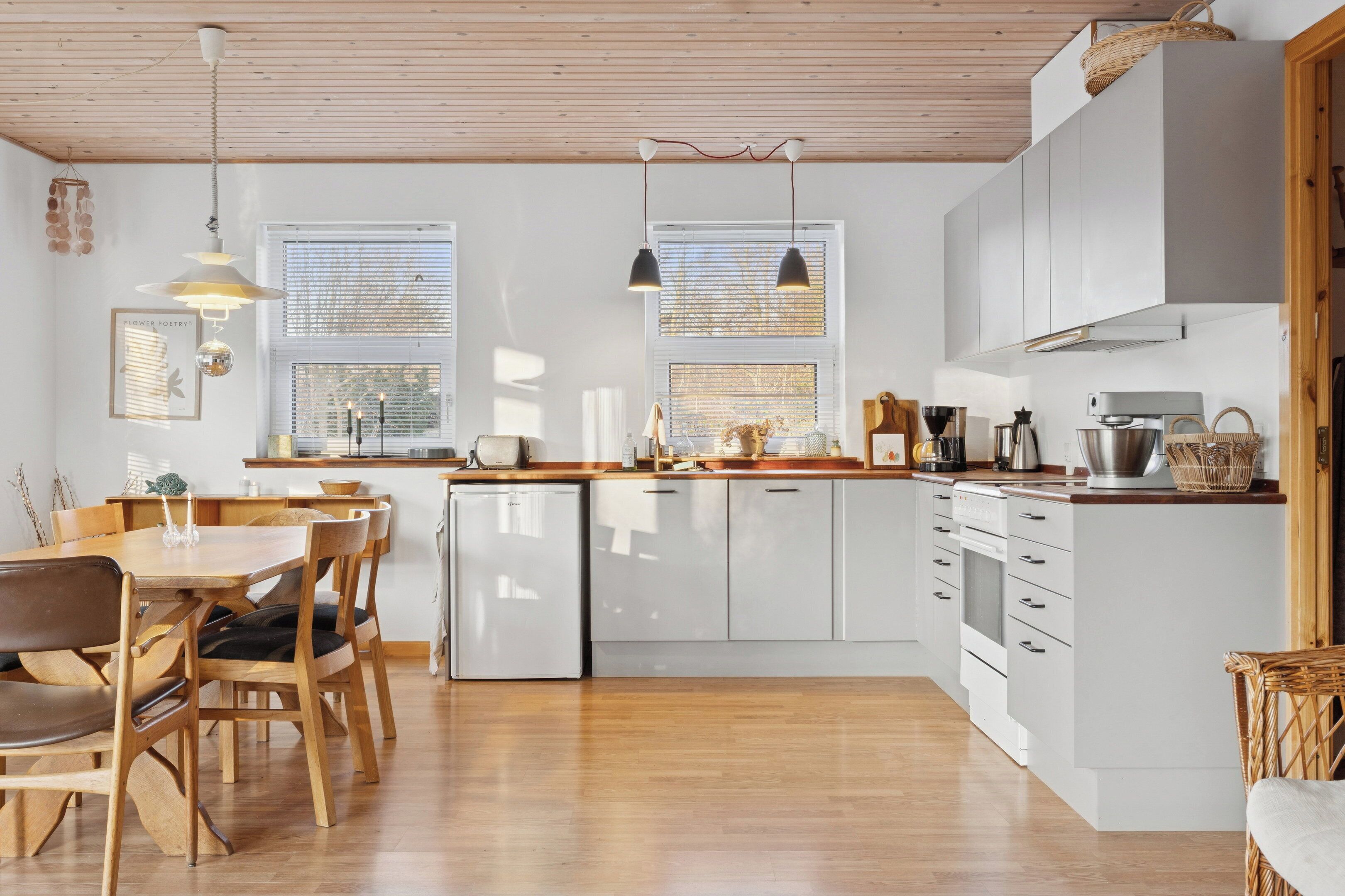 Een moderne keuken met witte kasten, houten aanrecht en een zithoek met een houten tafel en stoelen.