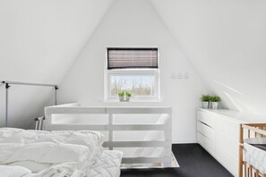 A bedroom with a bed, a white dresser, a window with blinds, and a small plant on the dresser. - Seafront holiday home 4 ppl 30 m sea (Otterup)