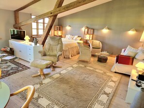 A spacious loft bedroom with a large bed, two chairs, a TV, and a desk. - Kornloftet beautiful home in old barn (Fejø)