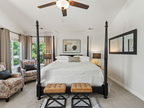 A four-poster bed with a ceiling fan, two ottomans, a large window with curtains, and a framed picture on the wall. - Grand Mountain Retreat: Hot Tub, Sleeps 21, Fire Pit, Mountain Views (Draper)