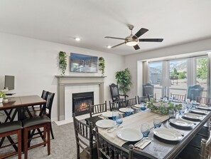 Une salle à manger avec une cheminée, un ventilateur de plafond et une grande fenêtre donnant sur un beau paysage.