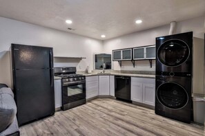 A compact kitchen with a refrigerator, stove, oven, dishwasher, and a washer-dryer unit. - Grand Mountain Retreat: Hot Tub, Sleeps 21, Sofa Sleeper on Main Floor (Draper)