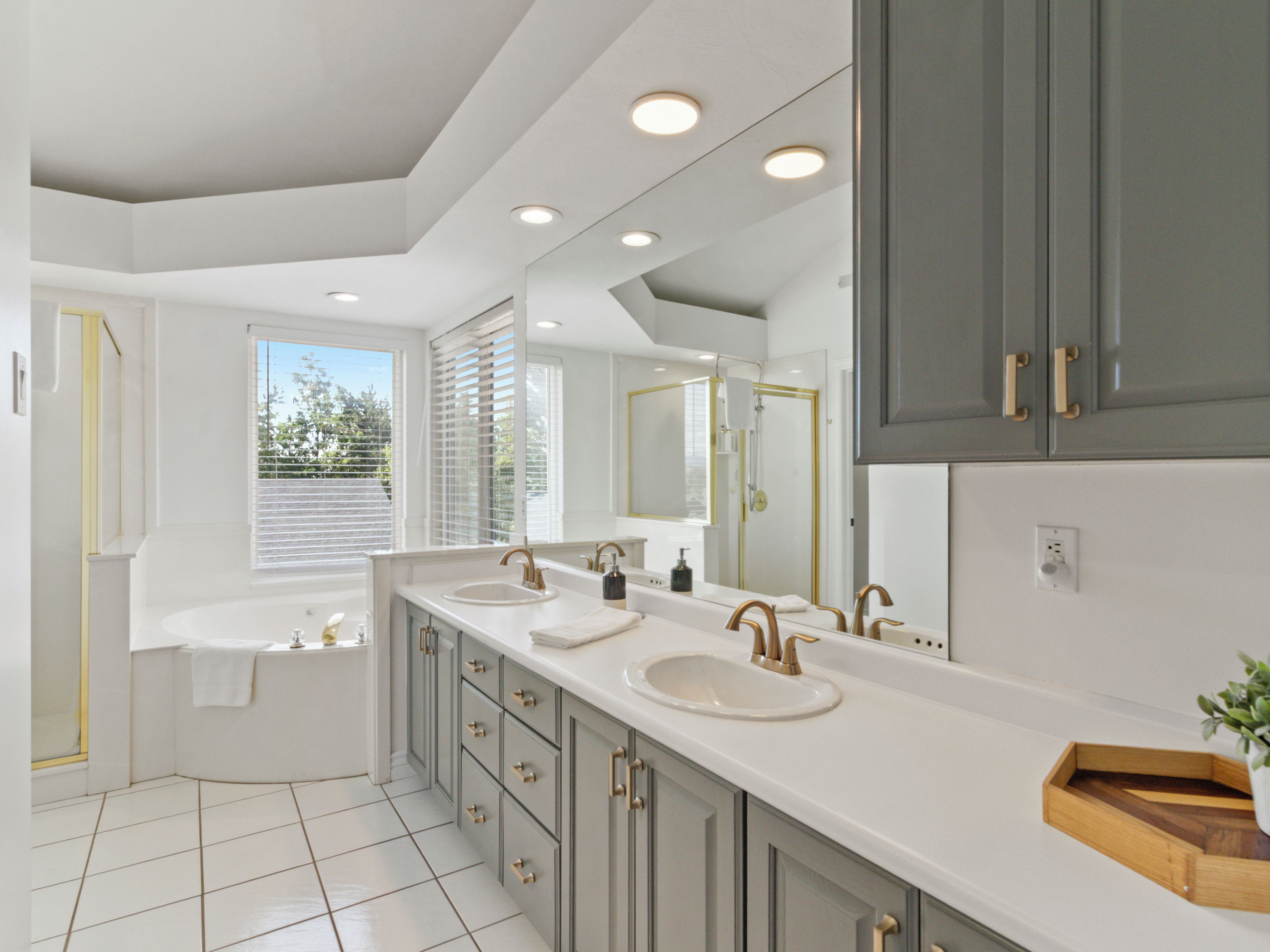 A modern bathroom with a large vanity, dual sinks, a bathtub, and a large mirror.