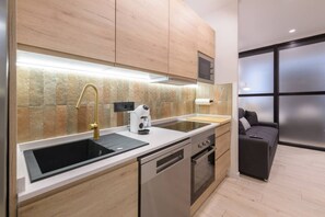 A modern kitchen with a built-in oven, a coffee machine, and a black sink. - Deluxe SOL, by MONARo 2BR 1BTH Exterior. (Madrid)