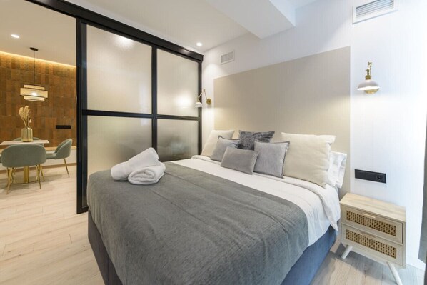 A modern bedroom with a large bed, bedside tables, a desk, and a chair. - Deluxe SOL, by MONARo: 2 bedrooms, 1 bathroom, outdoor area. (Madrid)