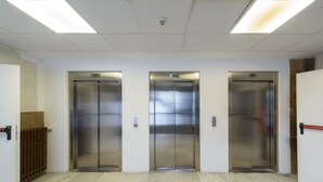 Un couloir avec trois ascenseurs, chacun étant indiqué par le numéro de l’étage auquel il donne accès.