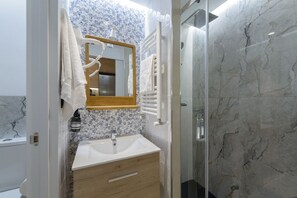 A bathroom with a marble sink, a mirror, and a shower. - Deluxe SOL, by MONARo: 2 bedrooms, 1 bathroom, outdoor area. (Madrid)