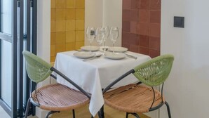 Un coin repas avec une table dressée pour quatre personnes, deux chaises vertes et une suspension.