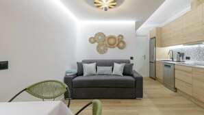 Un salon moderne avec un canapé gris, un fauteuil vert et une table à manger.