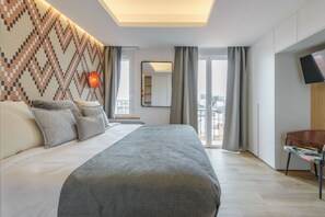 Een moderne slaapkamer met een groot bed, een kamer met behang, een televisie en een balkon met gordijnen.