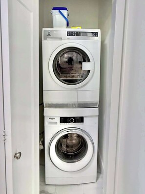 A compact, two-door laundry room with a top dryer and a bottom washer.