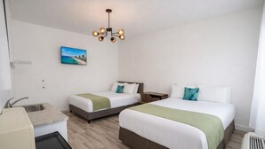 Une chambre d’hôtel avec deux lits, un bureau, un lavabo et un luminaire au plafond.