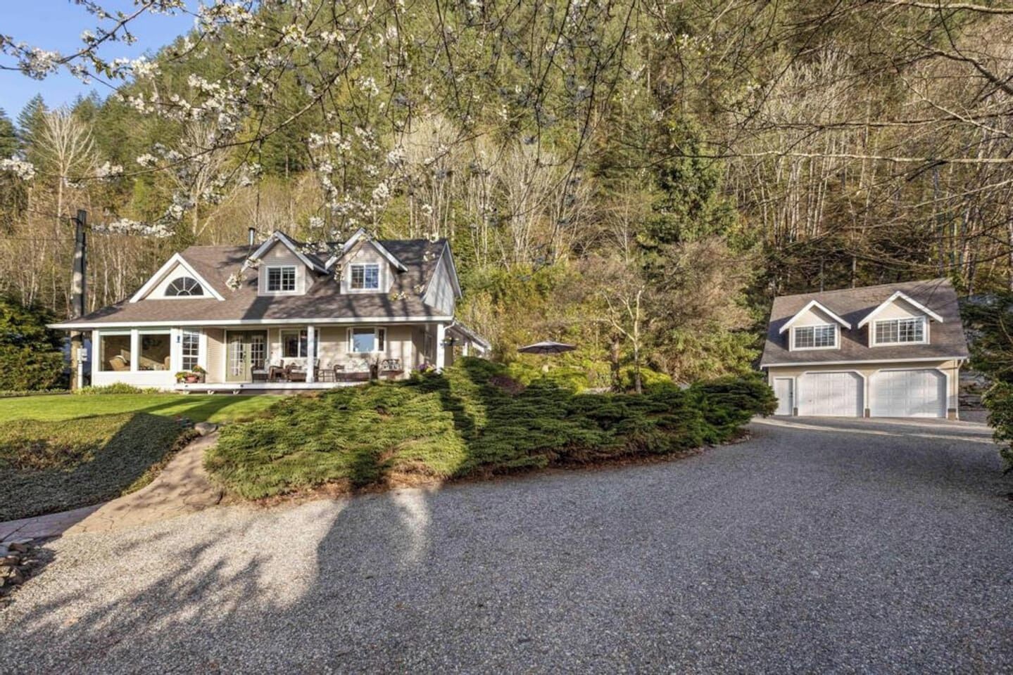 A two-story house with a covered porch, a garage, and a gravel driveway.