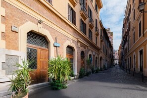 Une étroite rue pavée bordée de bâtiments historiques, avec des portes en arc de cercle et une enseigne indiquant « S. Francesco ».