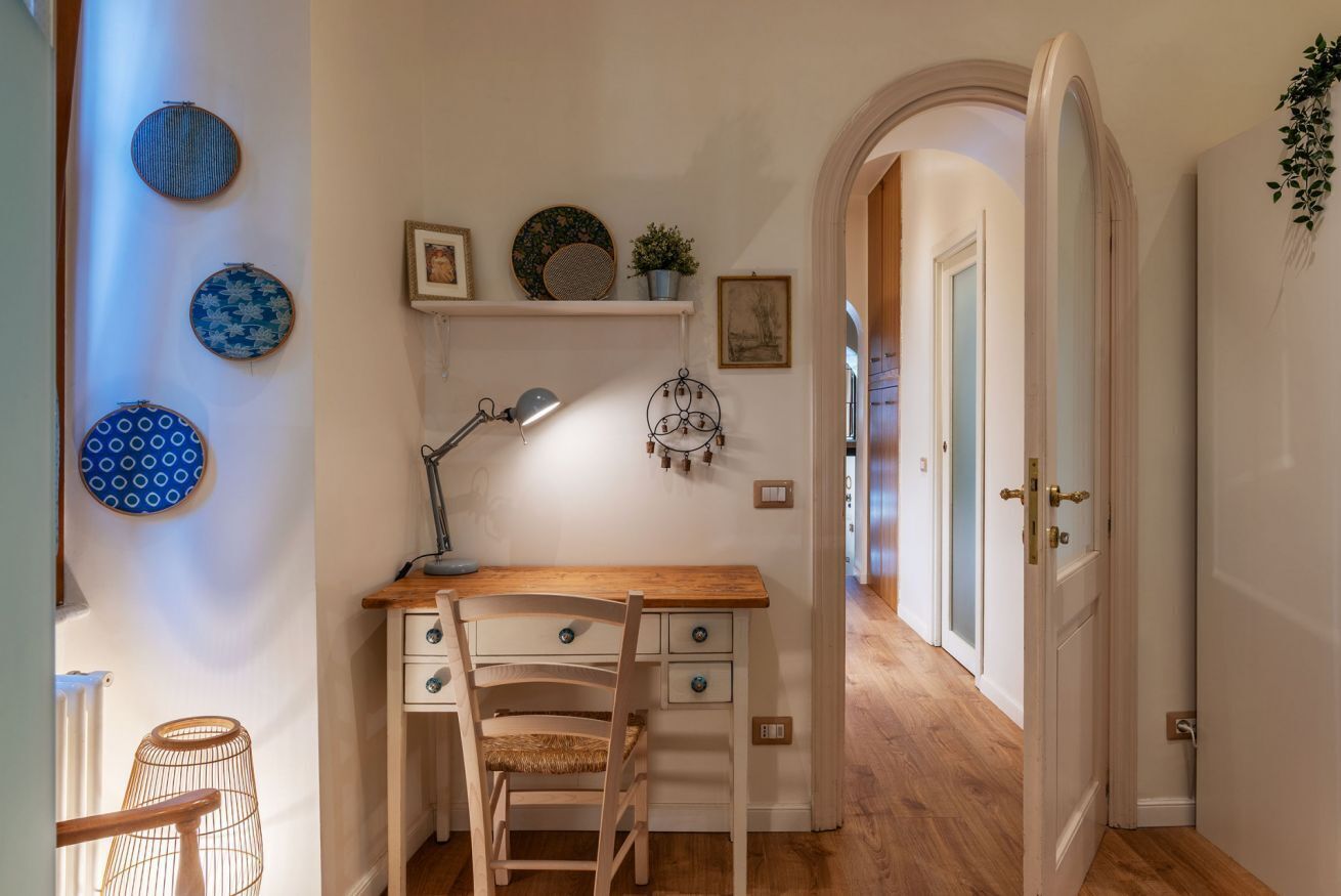 A study with a desk, chair, and shelves with decorative plates and a plant.