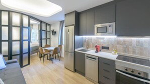 Moderni keittiö, jossa on sisäänrakennettu mikroaaltouuni, uuni ja astianpesukone. Keittiössä on myös ruokailutila, jossa on pöytä ja tuolit.
