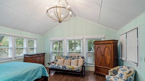 A bedroom with a bed, a sofa, a chair, a wardrobe, and a chandelier. - 5 Bdrm Beach House-Walk to Beach-Pet Friendly (North Myrtle Beach)