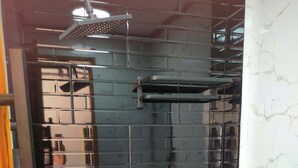 Ein Badezimmer mit schwarzer Fliesenwand, einer weißen Toilette, einer Duschkabine und einem Handtuchhalter.