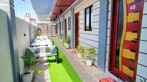A corridor with a green artificial turf, potted plants, and a red door with the number 05. - Kabayan Hotel (Aliaga)