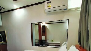 A hotel room with a bed, a mirror, an air conditioning unit, and a small table with a bottle. - Kabayan Hotel (Aliaga)