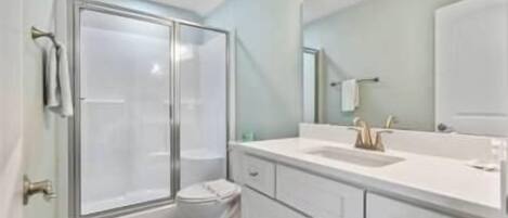 A modern bathroom with a glass shower enclosure, a white sink, and a large mirror.