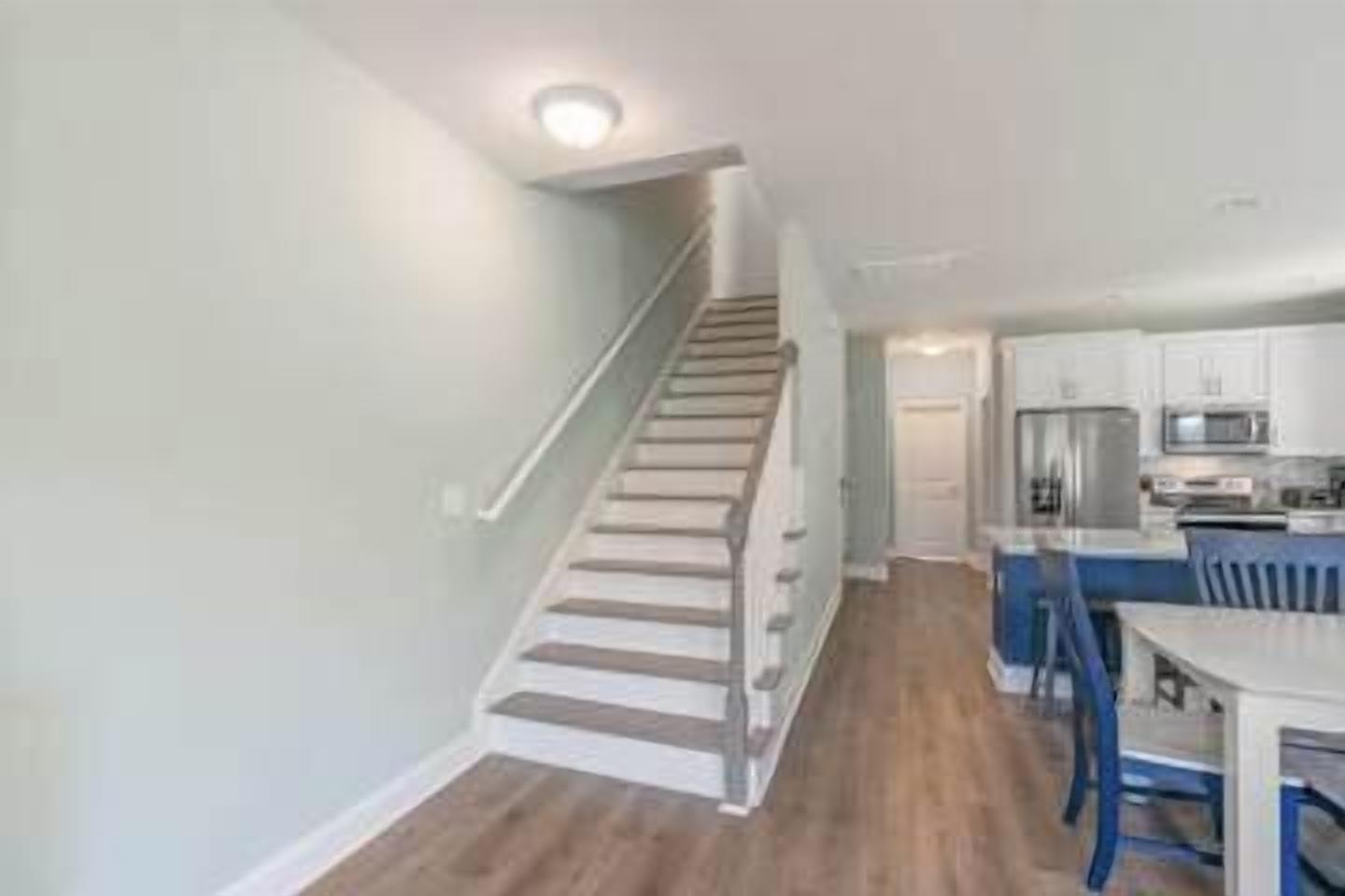 A modern kitchen with white cabinets, a stainless steel refrigerator, and a blue dining area.