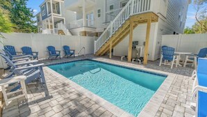 Una piscina con sillas azules y una terraza de madera.