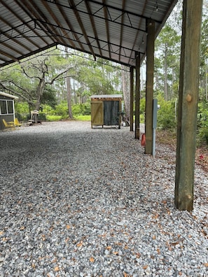 A covered outdoor area with a gravel floor, wooden posts, and a small wooden structure.
