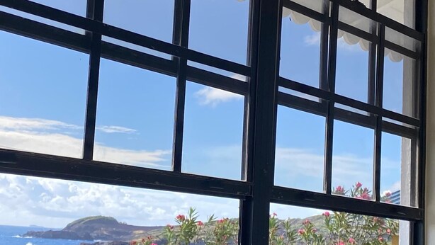 Ein Fenster mit Blick auf das Meer und die Küstenlandschaft.