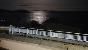 Nachtsicht auf eine Küstenlandschaft mit hellem Mond und fernen Hügeln.