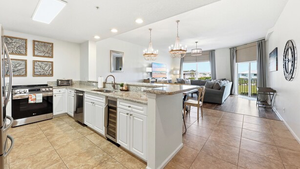 A modern kitchen with white cabinets, a central island, and stainless steel appliances. - Ocean Park Breeze - Walk to Beach Pool and Heated Spa (Fernandina Beach)