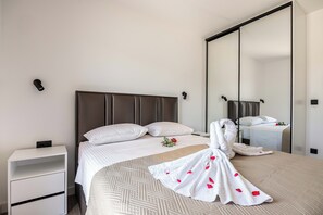 A neatly made bed with a white duvet, a headboard, and a bedside table with a lamp. - Skyline Residence 2 (Bigova)