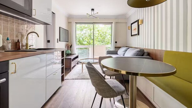Et moderne køkken med spiseplads, sofa og TV.