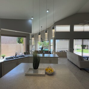 A modern kitchen with a central island, pendant lighting, and large windows. - Wonderful 5-bedroom house in welcoming Gilbert (Gilbert)