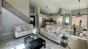 A spacious living area with a staircase, two sofas, a coffee table, and a dining area with a chandelier. - Wonderful 5-bedroom house in welcoming Gilbert (Gilbert)