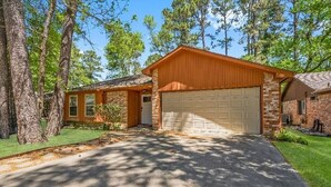 A two-story house with a garage, surrounded by trees and a well-maintained lawn. - Quaint 3-bedroom house with AC in charming Spring (Spring)