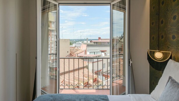 A hotel room with a balcony, a bed, a headboard, and a view of the cityscape. - GRAN VIA capitals, LAS VEGAS (Madrid)